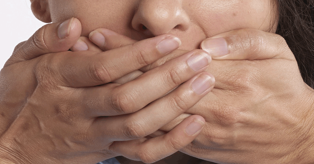 Hands over mouth illustrating self-censorship and academic freedom