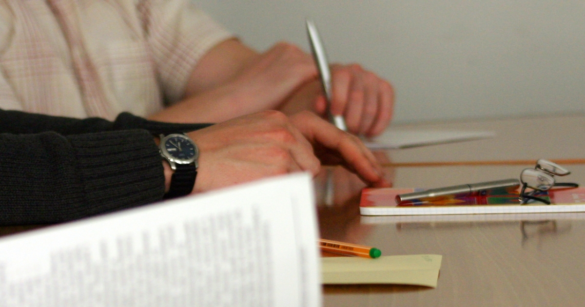 Hands on table with papers and pen